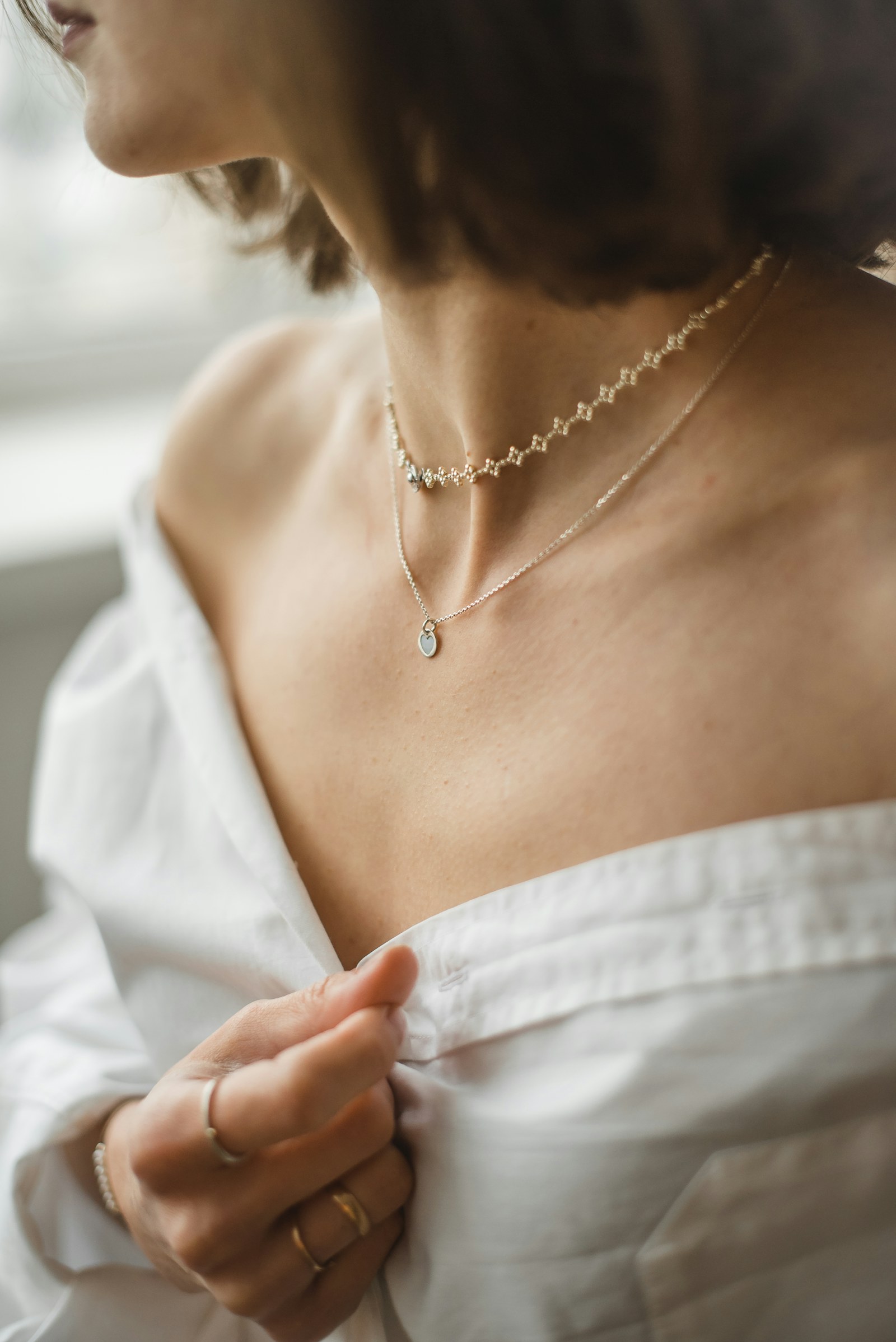 Mujer con camisa blanca y collares de oro superpuestos
