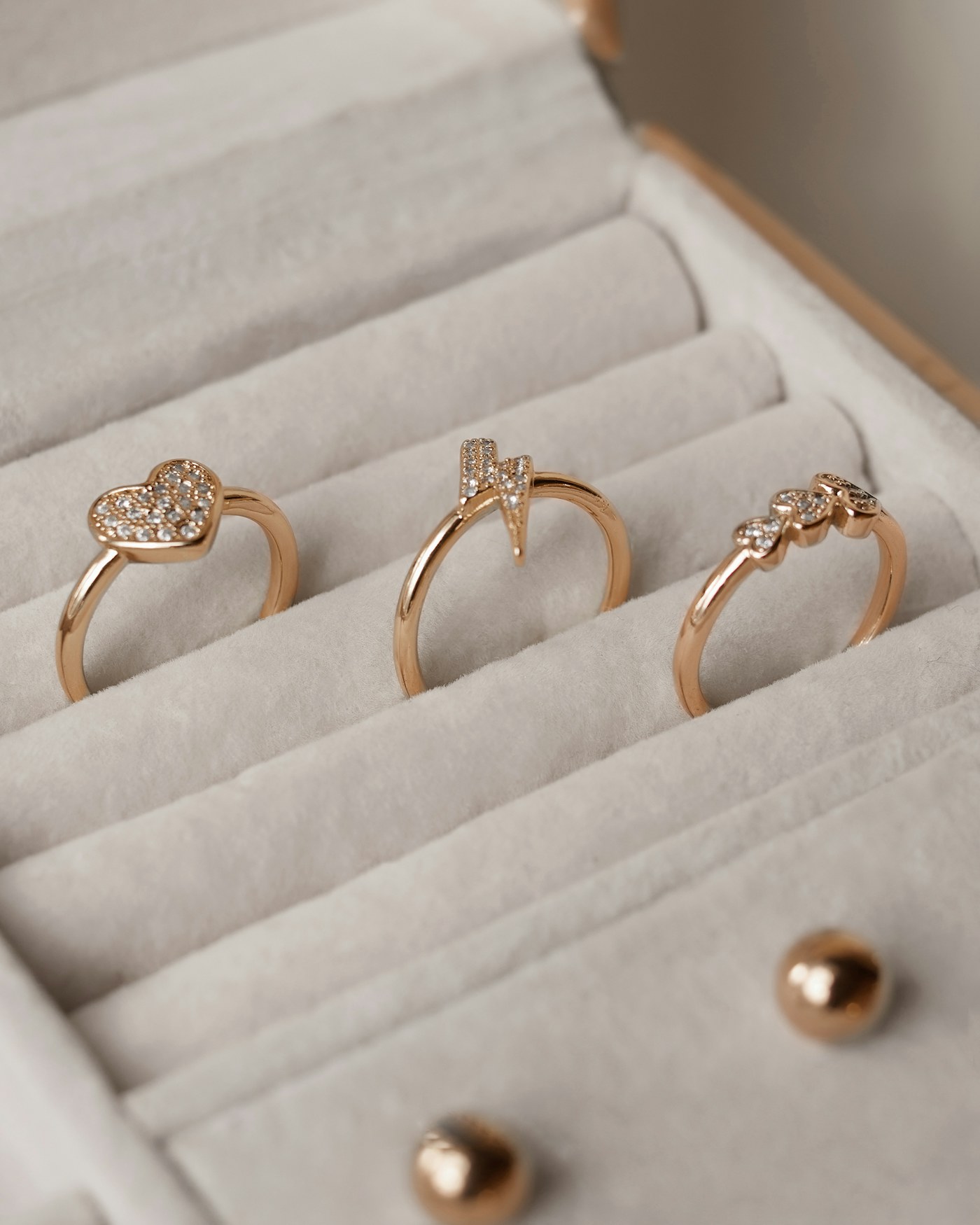 Tres anillos de oro rosa con diamantes en un joyero
