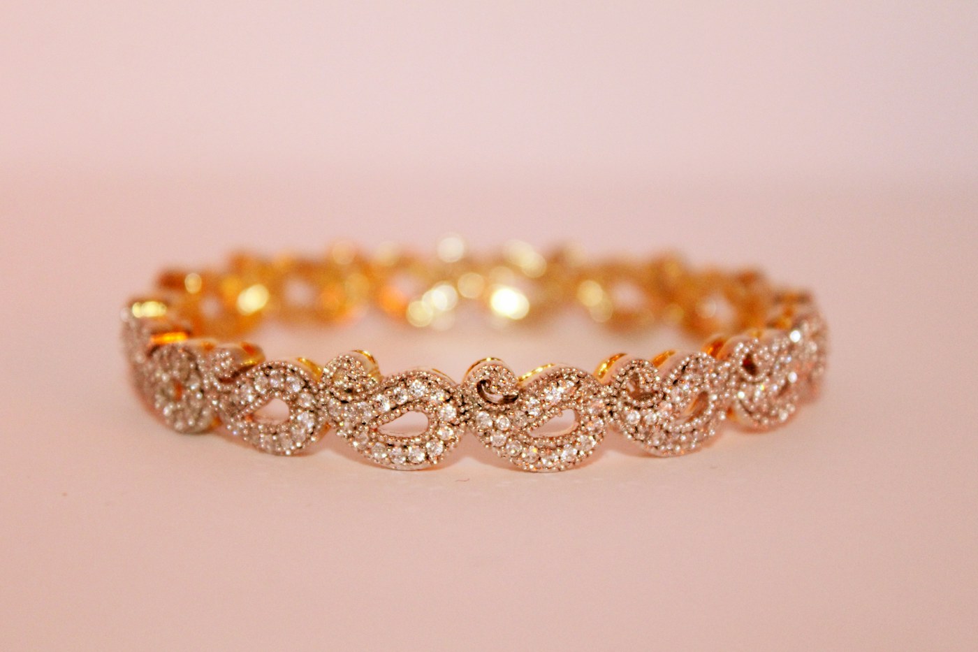 Brazalete de oro rosa con diamantes sobre fondo empolvado